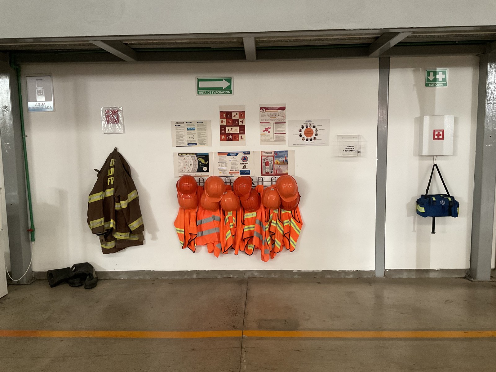Safety equipment station with hard hats, vests, fire jacket and first aid kit