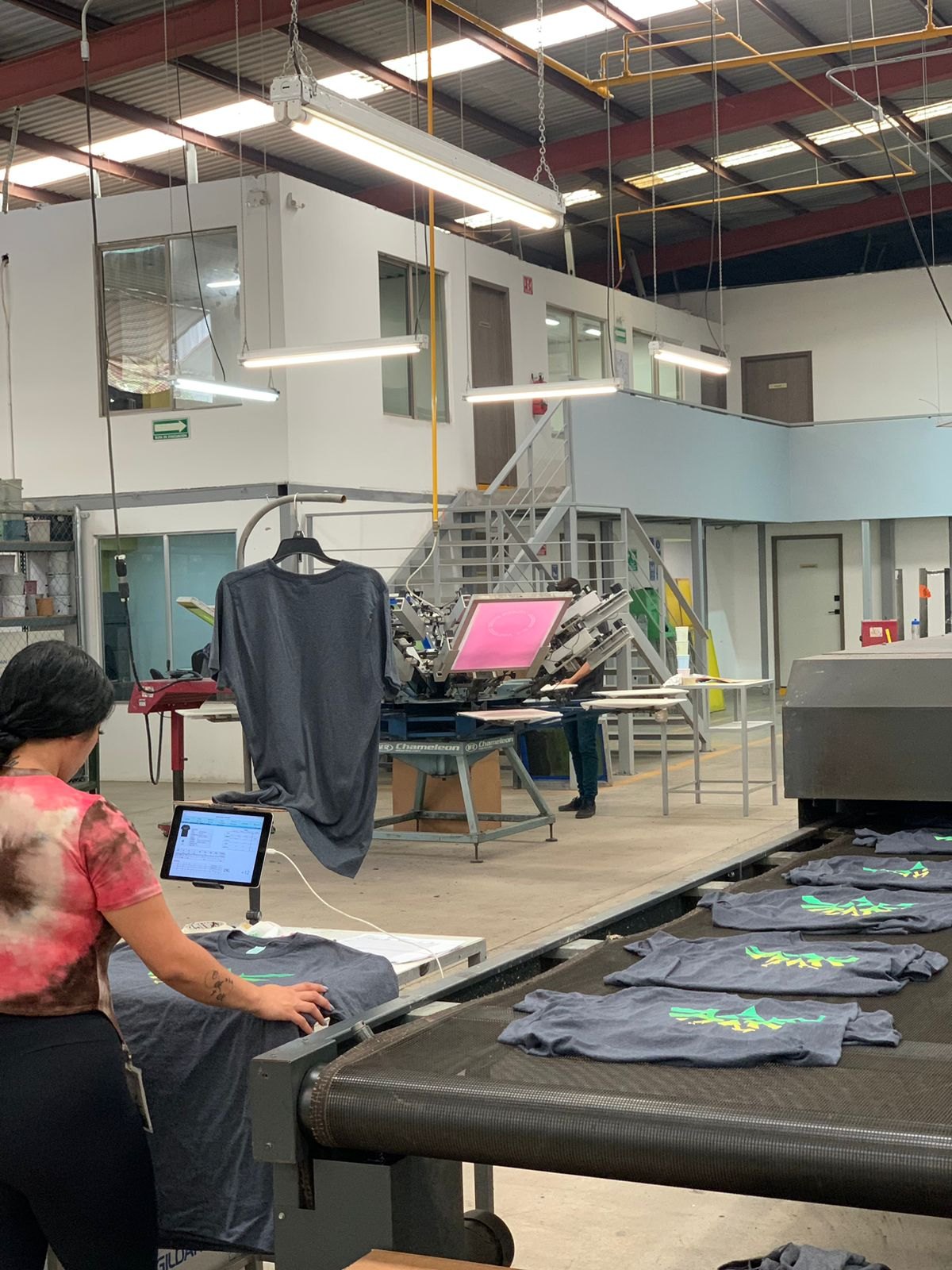 Production floor with screen printing press and conveyor